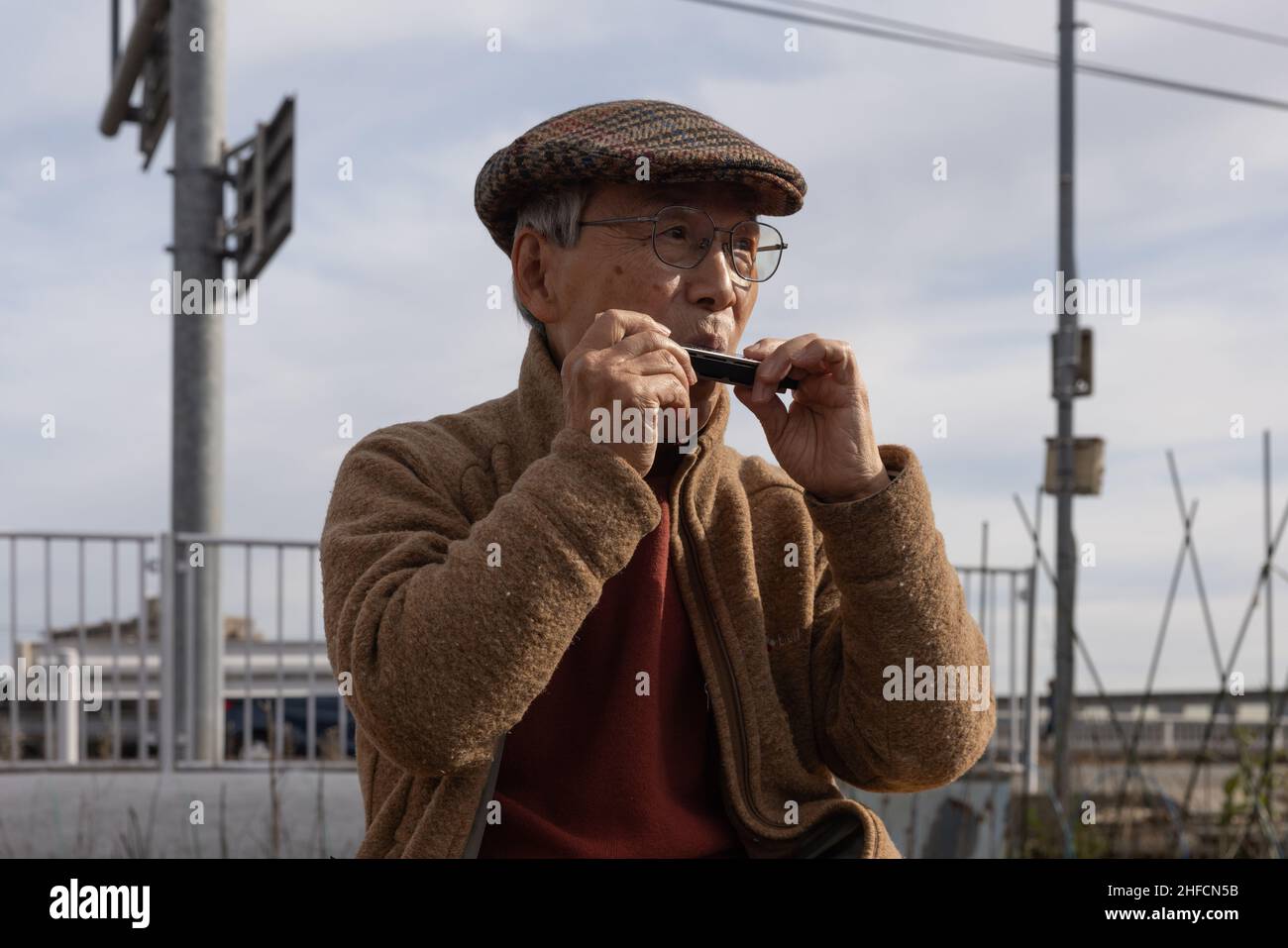 Senior citizen plays a harmonica during Dondo-Yaki in  is  a traditional event usually held in mid-January and is considered the end  of New Year celebrations in Japan. During this event Shimekazari (