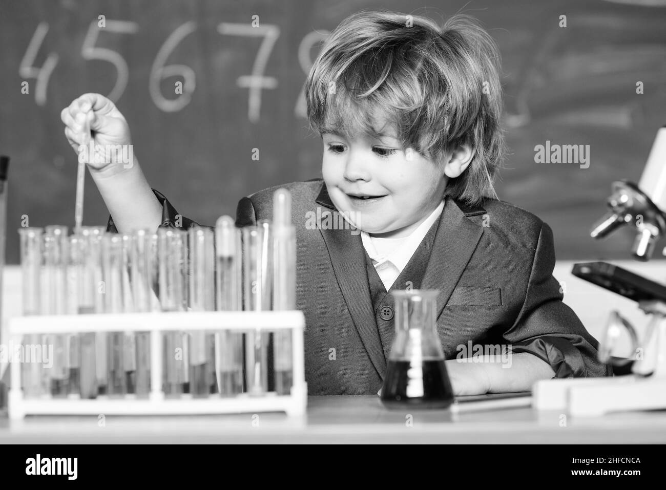 Little kid learning chemistry in school laboratory. Little boy at chemical kid in lab