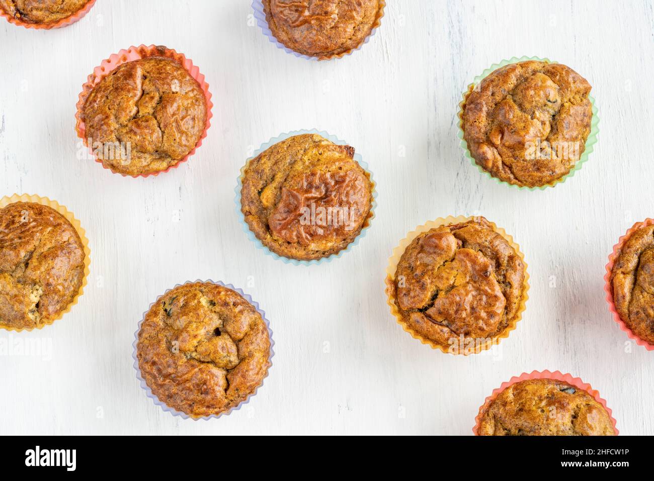 top view homemade muffins in colorful silicone molds on white table or background. gluten and sugar free small healthy cakes with fruit. food concept Stock Photo