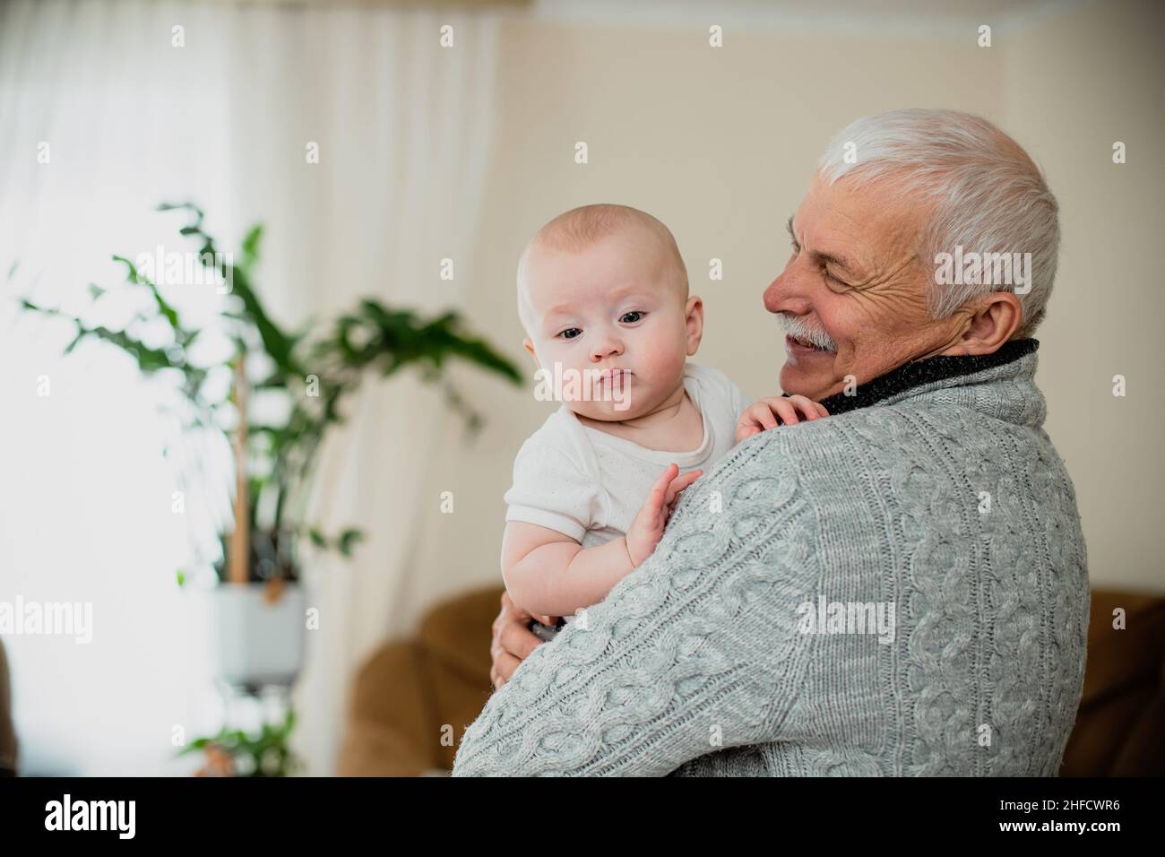An elderly man holds his granddaughter. Happy grandfather with a little ...