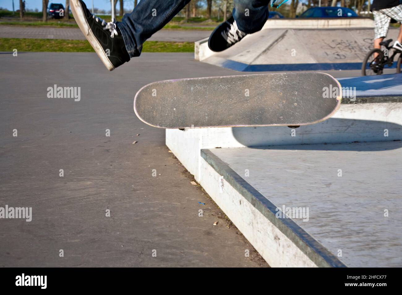 boy with scateboard is going airborne at a skate park Stock Photo