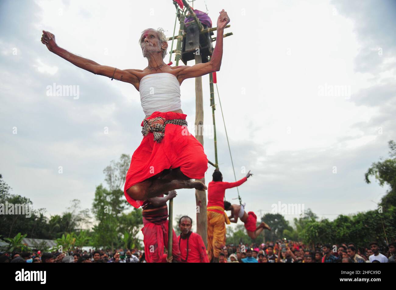 Devotees with hooks piercing the skin of their backs are hung with ropes, as part of the Charak Puja Festival ritual, during Poush Shonkhanti of Bangl Stock Photo