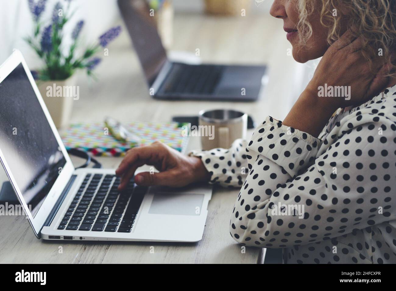 Office workstation closeup with adult woman using laptop and online connection wireless. Neck pain and bad posture problems for workers people at the Stock Photo