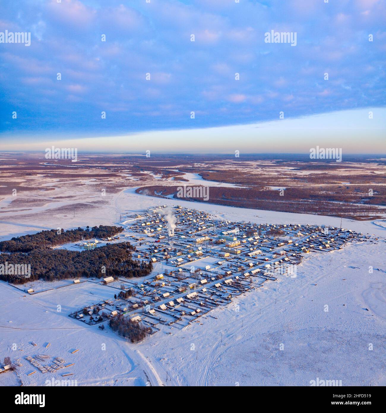 Rural timber houses and barns are on winter river in Siberia. Russian ...