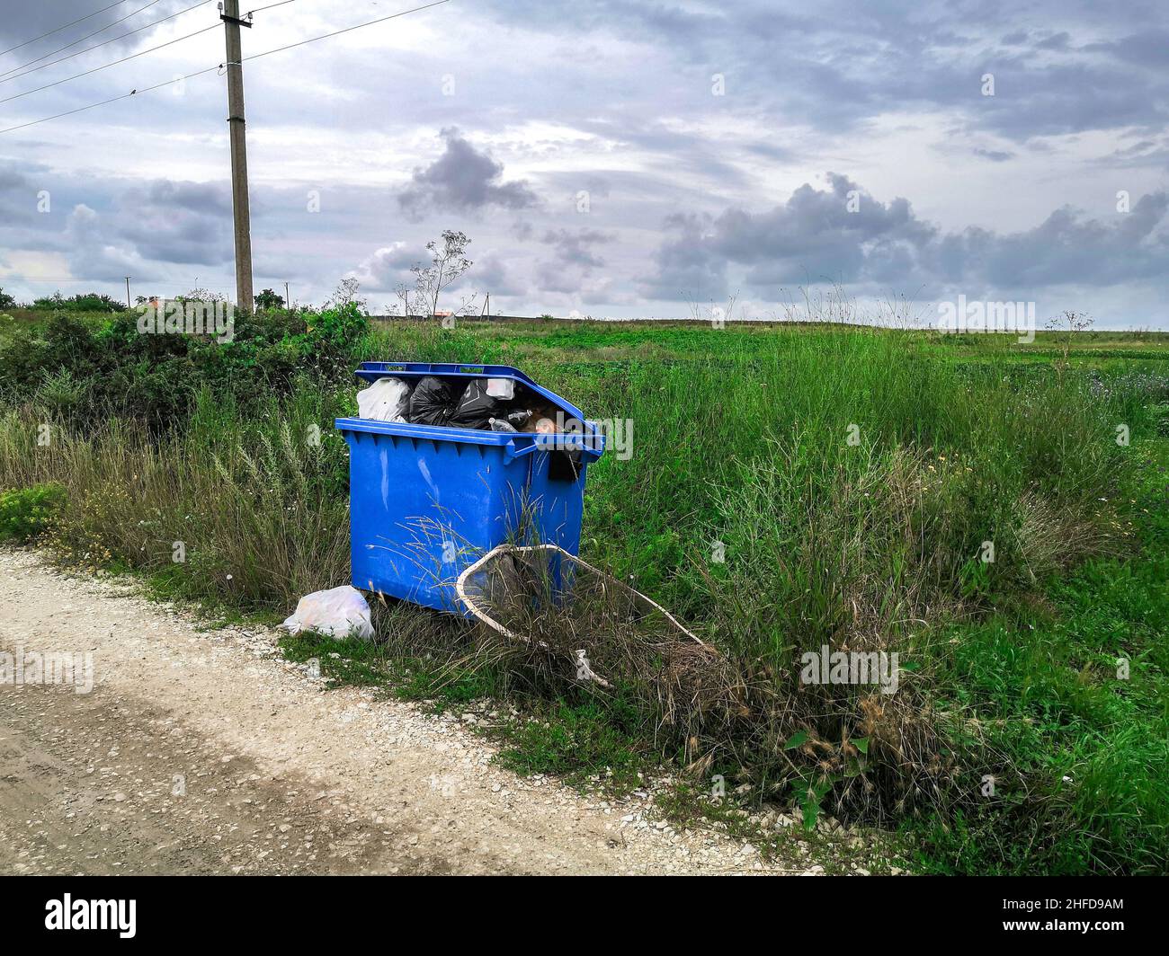Overflowing garbage container on the side of the road in the village