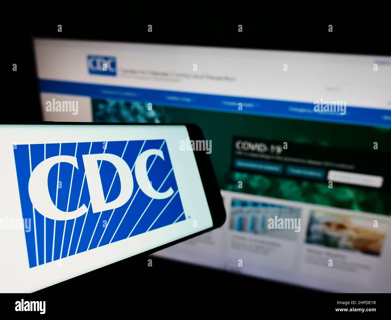 Cellphone with logo of Centers for Disease Control and Prevention (CDC) on screen in front of website. Focus on center-left of phone display. Stock Photo