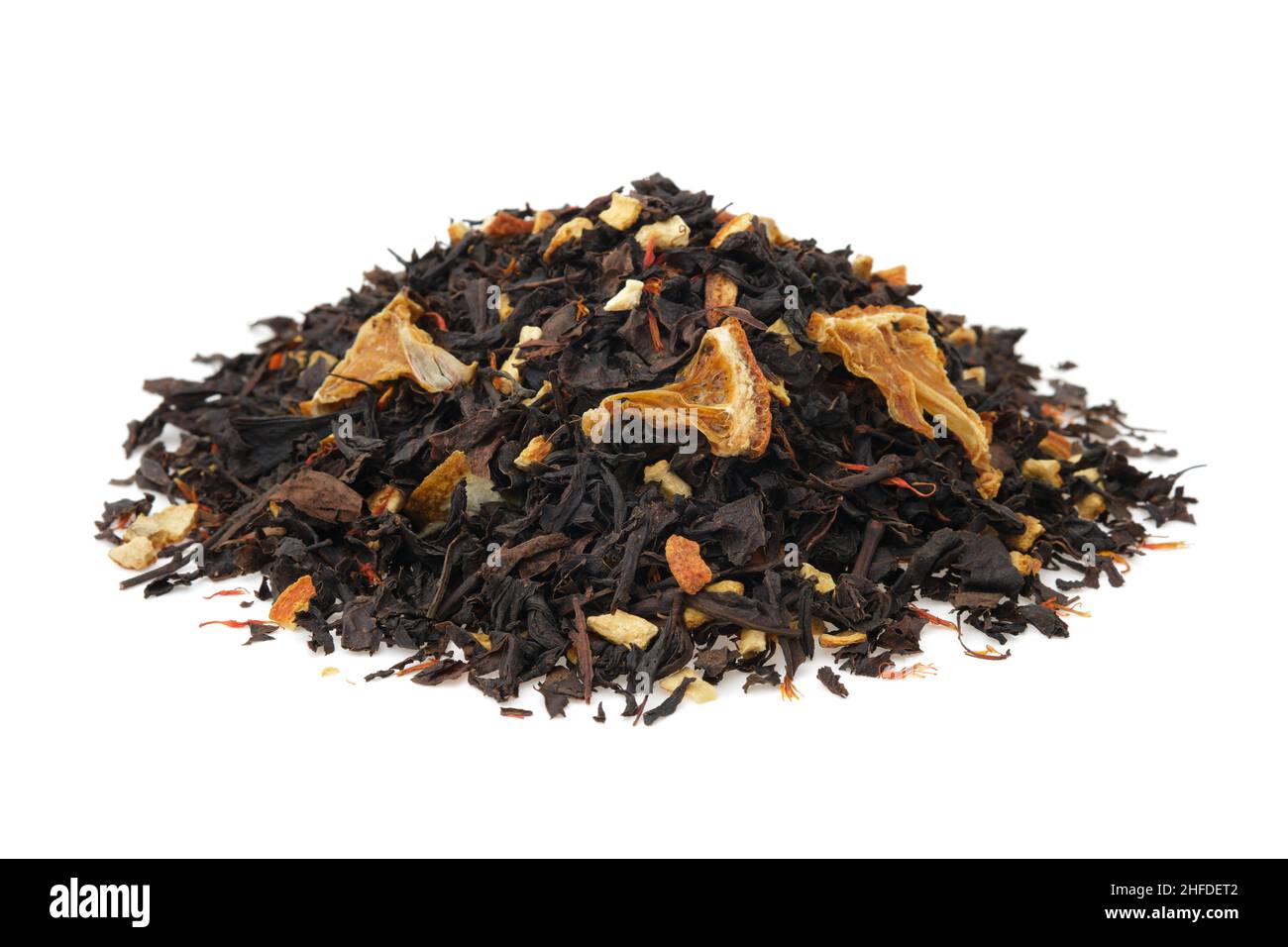 Pile of dry black tea leaves on white. Heap of aromatic black tea leaves with dried citrus slices and peel. Stock Photo
