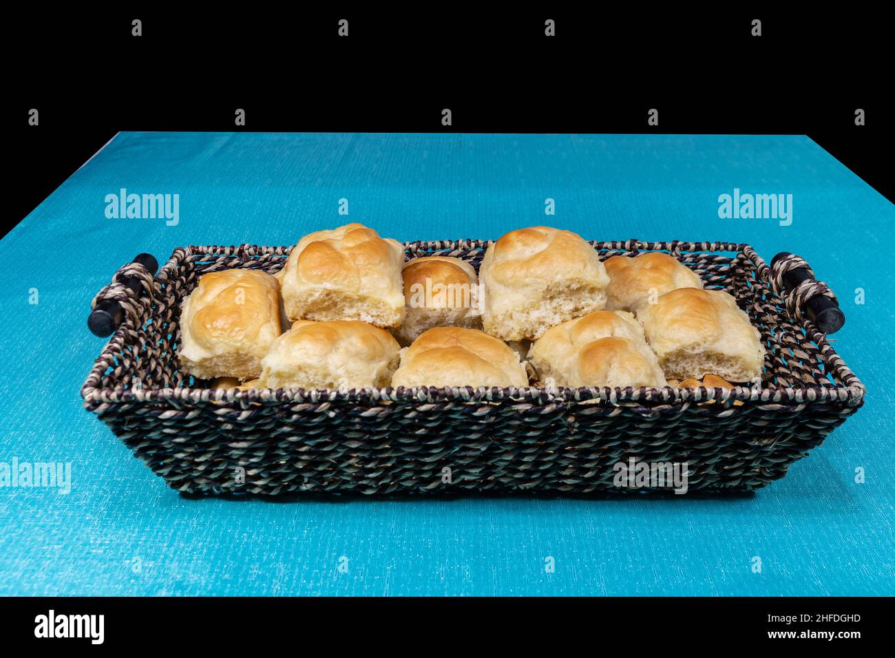 A basket of fresh baked, home cooked dinner rolls with fluffy texture and golden brown crust in a wicker basket on a table waiting to be served. Stock Photo