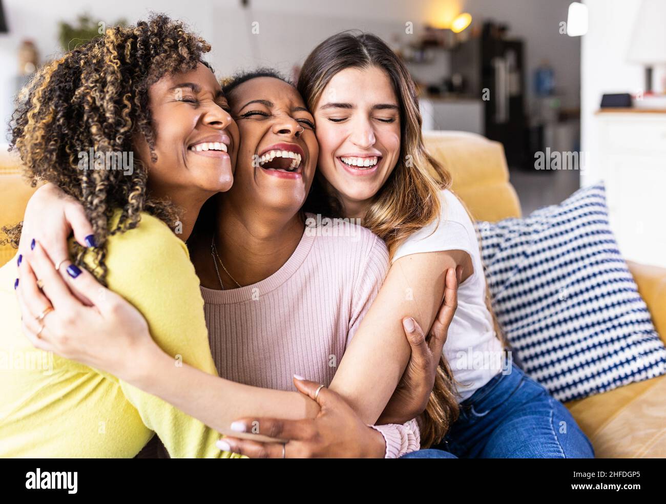 Three happy multiethnic female best friends laughing together at home Stock Photo