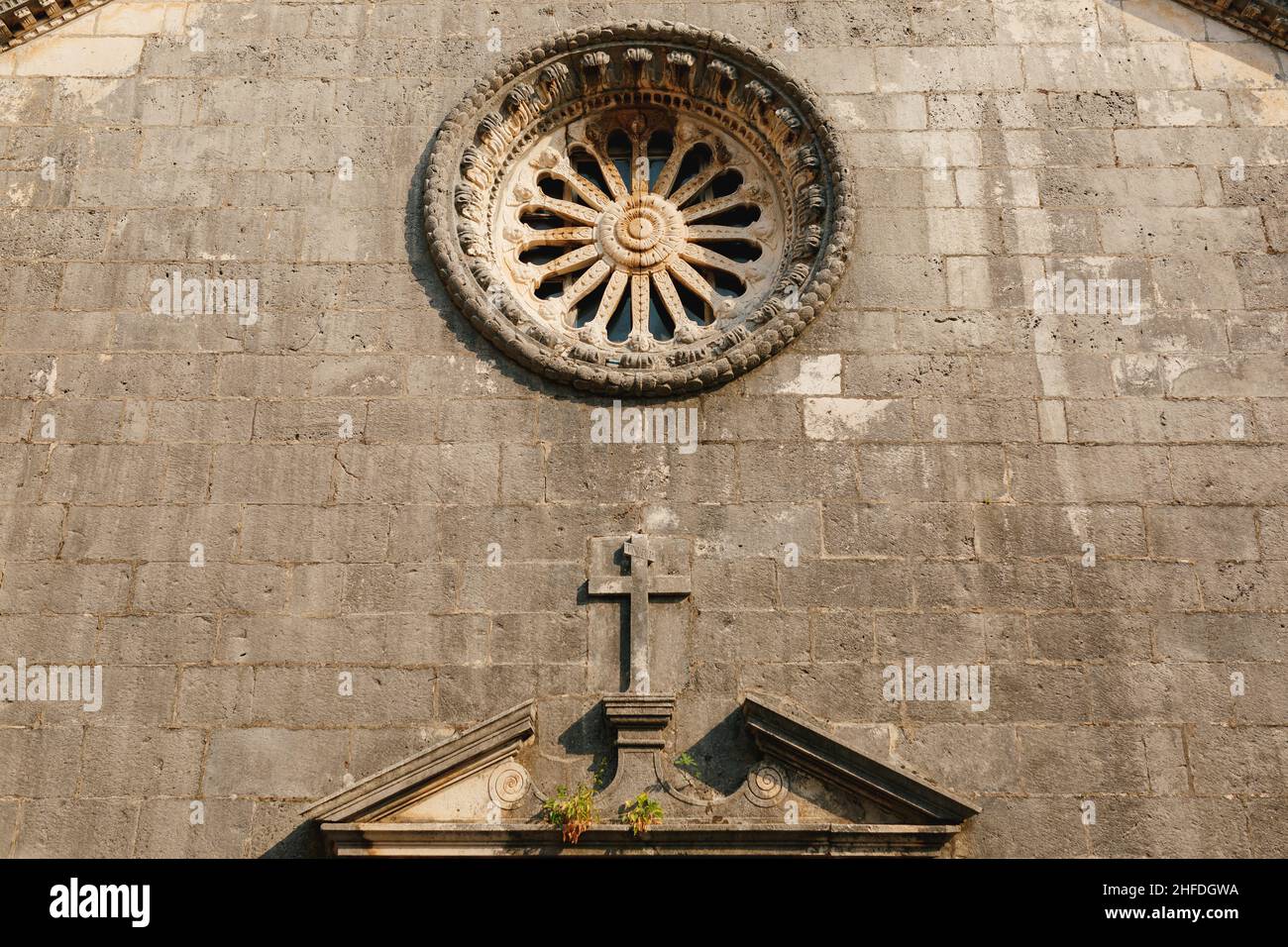 Rose window with ornaments on the dark stone wall of the church above ...