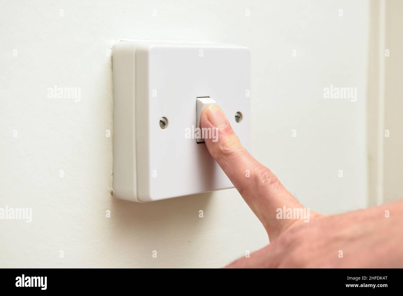 Person turning off light switch to save on energy bills and waste of electricity Stock Photo Alamy