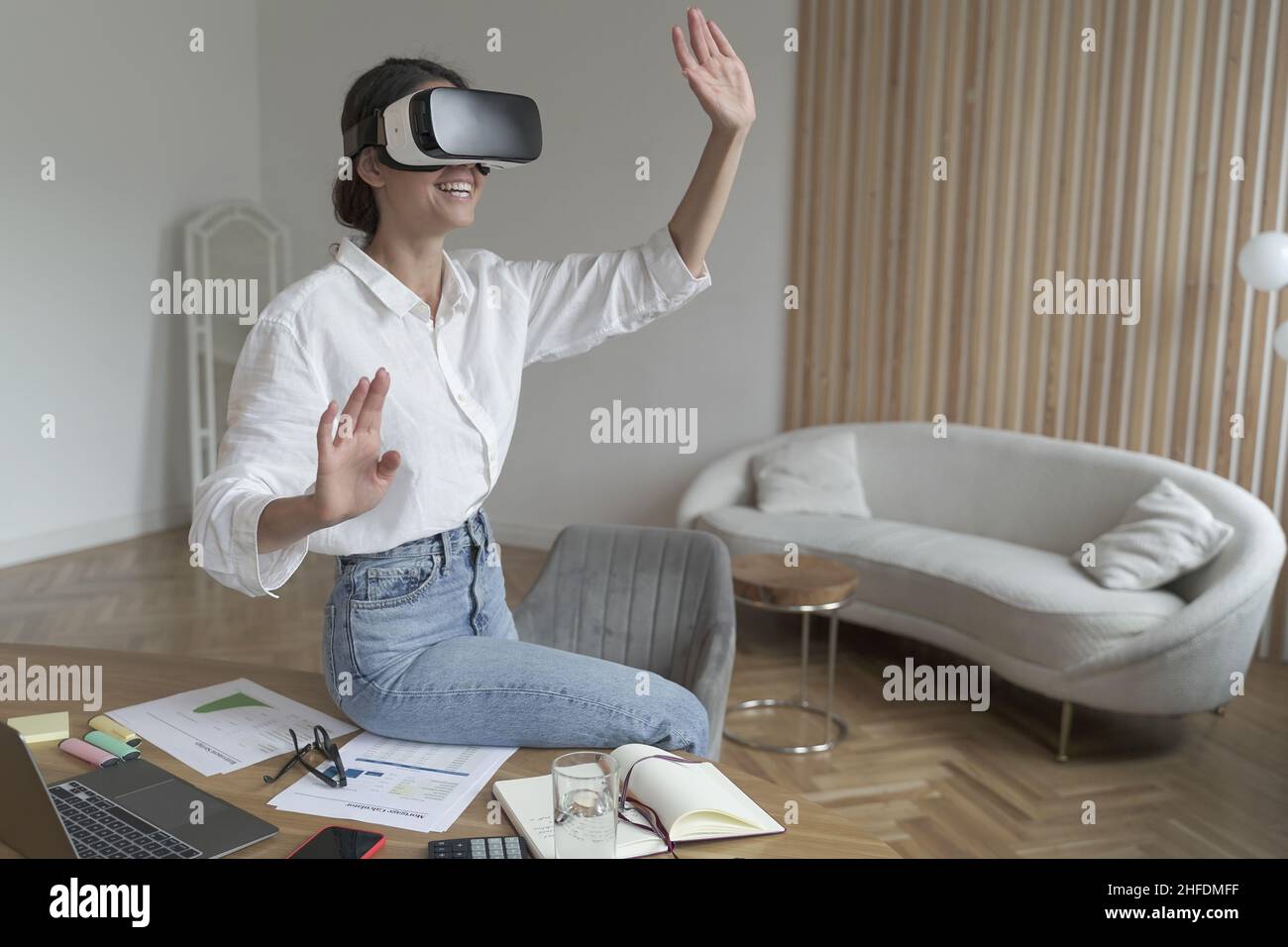 Businesswoman in VR headset on head touching 3d objects while working in modern office Stock Photo