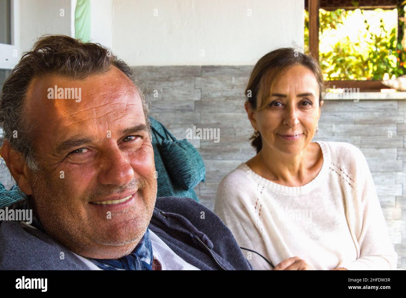 Portrait of middle aged couple. Middle aged couple looking at camera and smiling cheerfully. Family portrait concept. Retired couple relaxing at home. Stock Photo