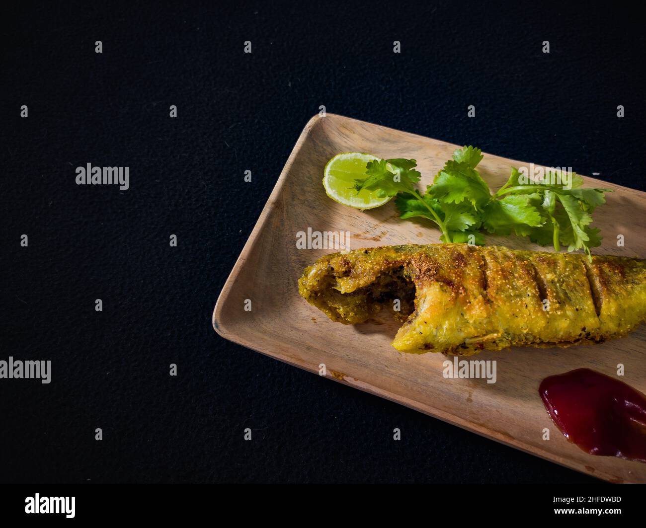 whole fish fry served on wooden plate garnished with lemon, coriander