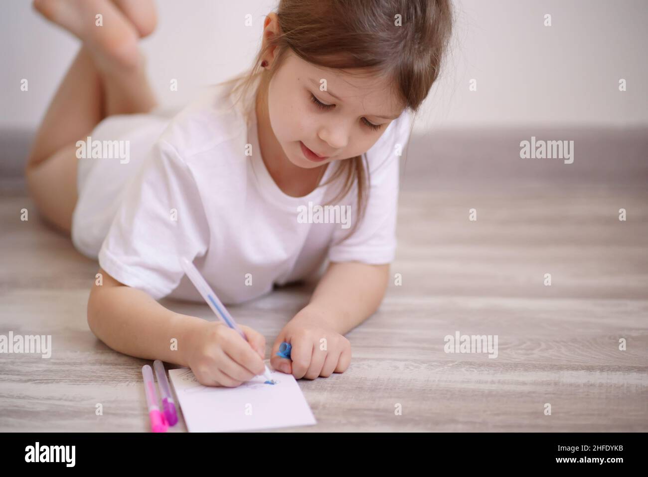 Little girl lies on the floor and draws Stock Photo - Alamy