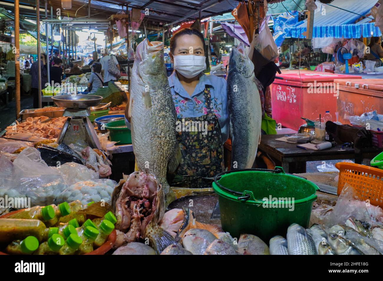 A fish vendor at (market) Talat Phlu in Thonburi area, Bangkok, Thailand, is holding up two large fish Stock Photo