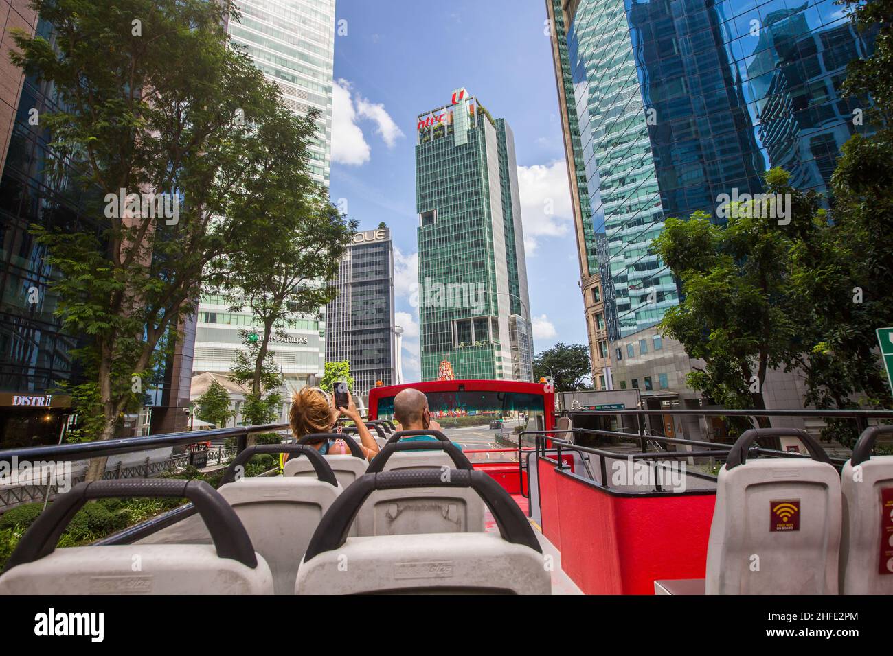Tourists sitting on open top bus taking pictures of Singapore Central Business district commercial offices building. Stock Photo