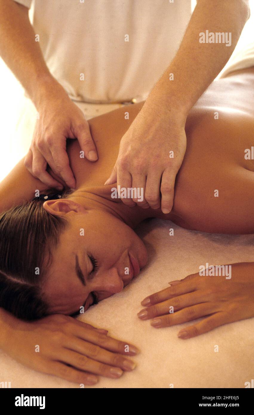 dark hair young girl expressive profile body lay down on a tabble physiotherapist massage her shoulder Stock Photo
