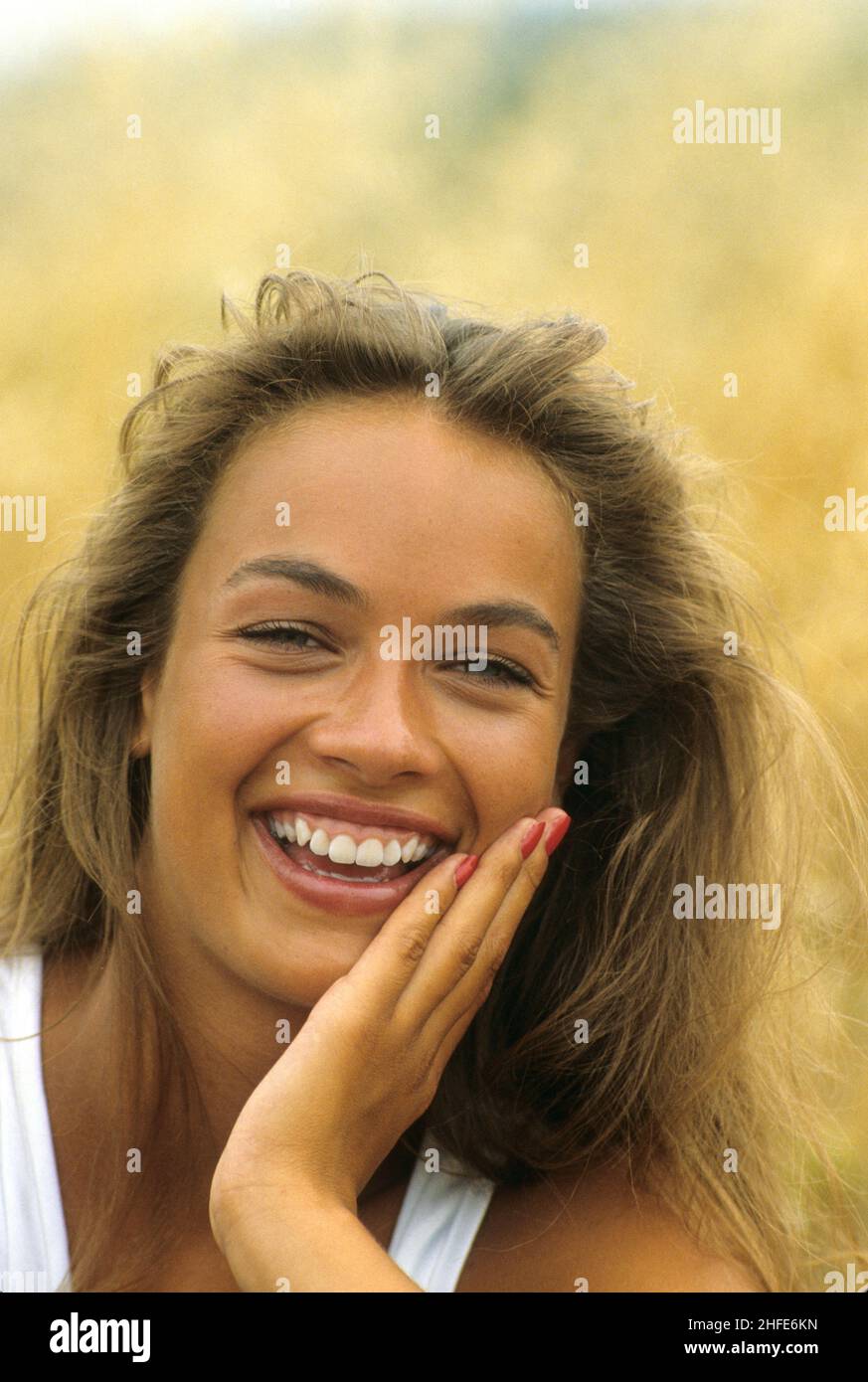 smiling and happy blond hair young woman portrait looking front camera yellow herbs background Stock Photo