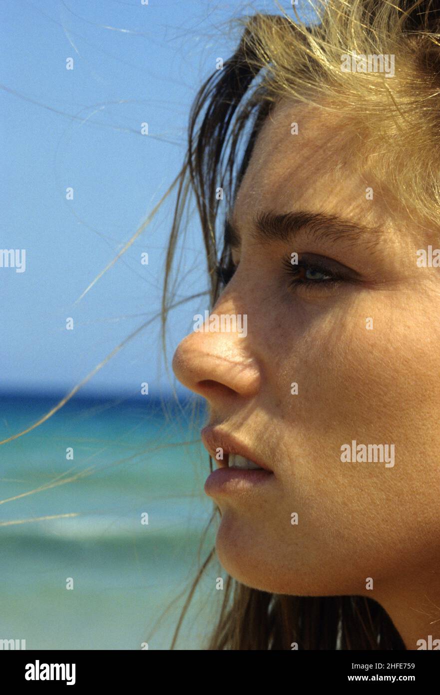 Pretty blond hair beauty happy looking smiling portrait profile close up blue sky and seawater on background looking horizon Stock Photo