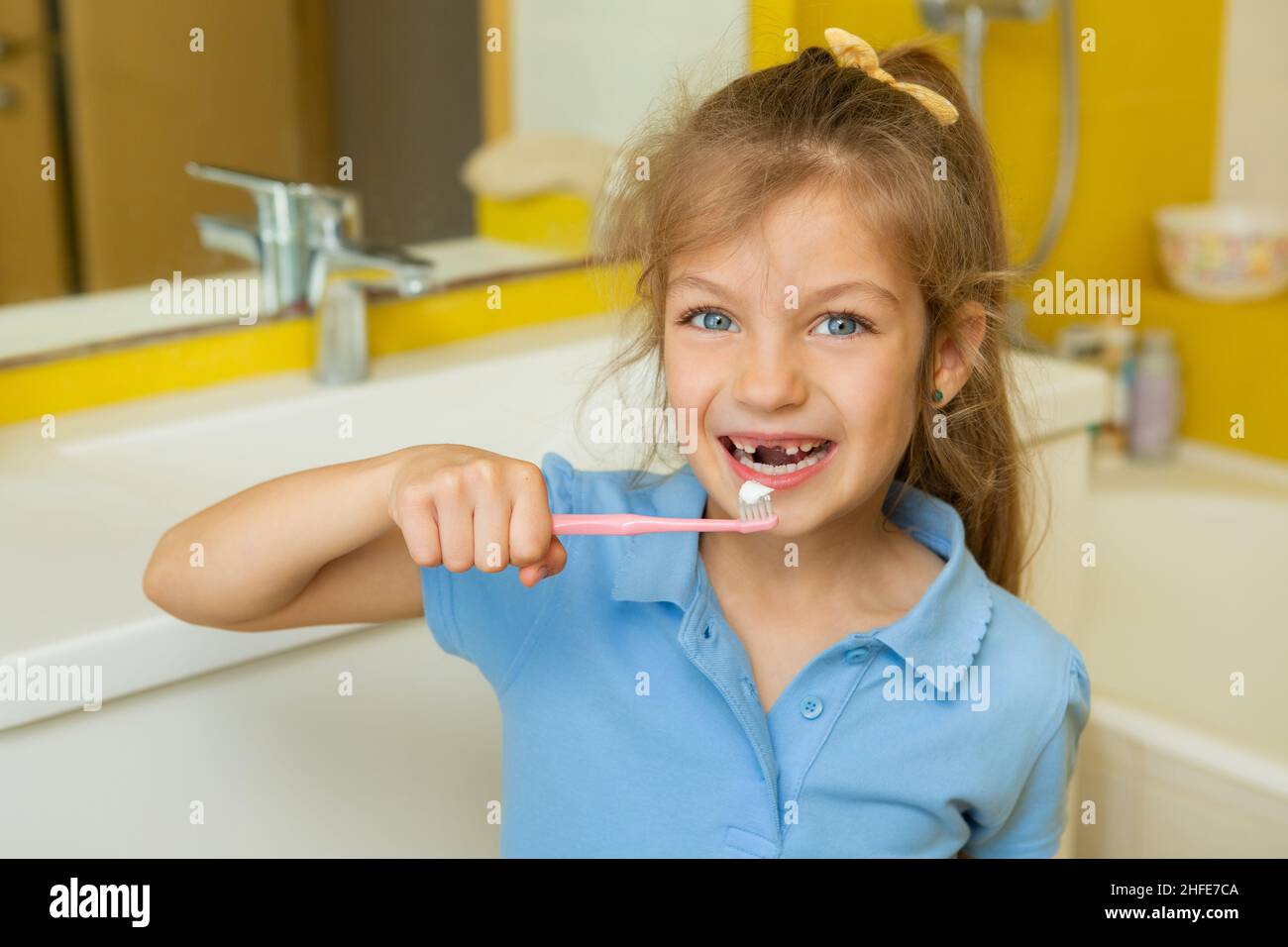 Beautiful little girl brushing teeth in bathroom. Healthy concept and