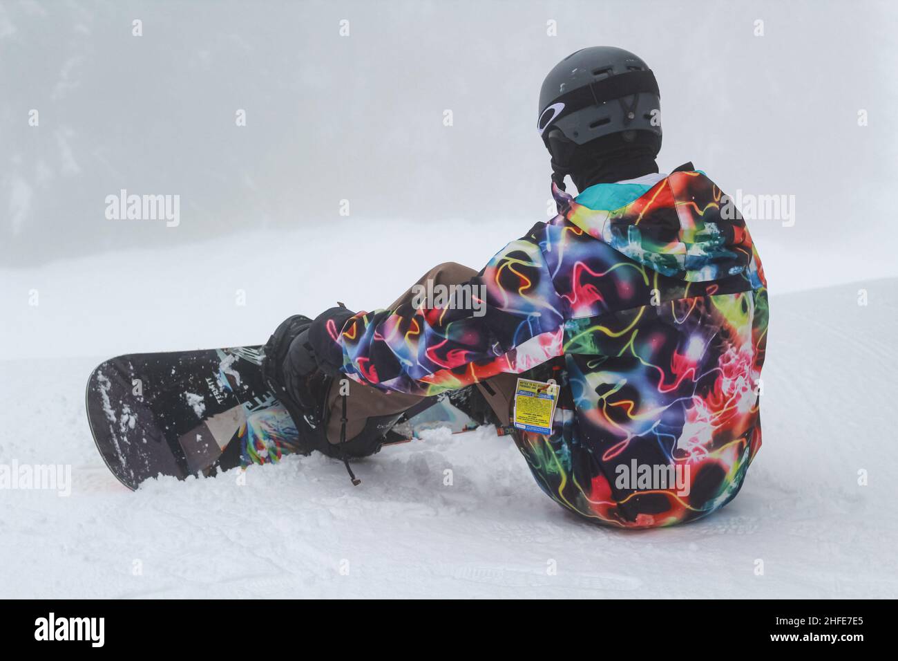 Snowboarder sitting on snow and see at mountains during snowing-February 4,2021-Seymor, BC, Canada. Travel photo, selective focus, copy space for text Stock Photo