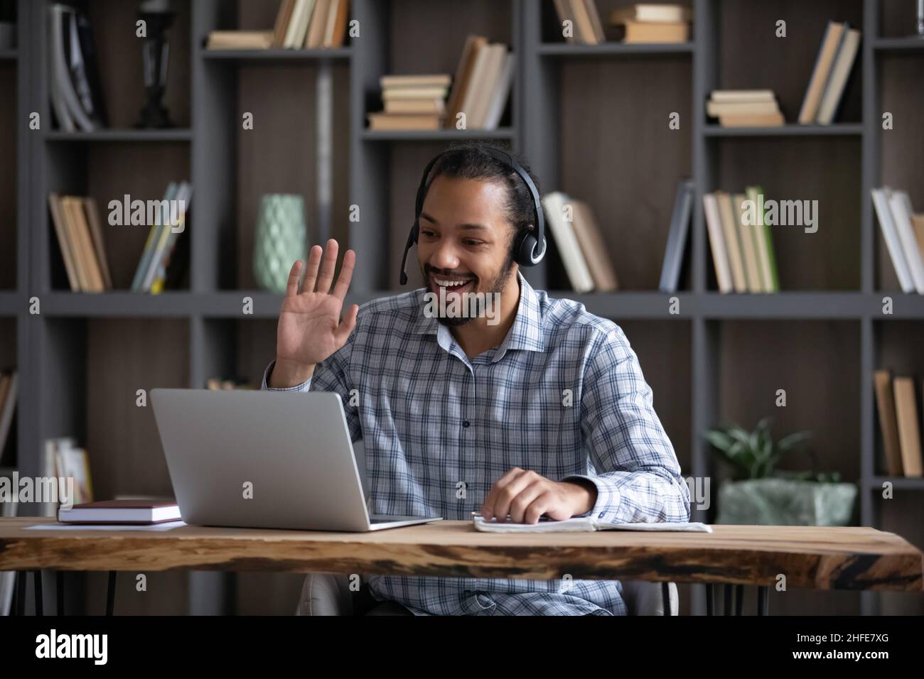Friendly African guy in headphones with mic waving hand hello Stock Photo