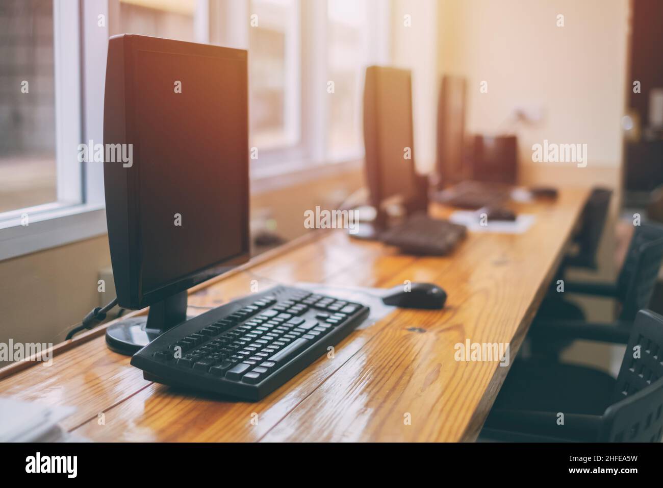 row of computer desktop on wood counter bar for internet service in internet cafe Stock Photo