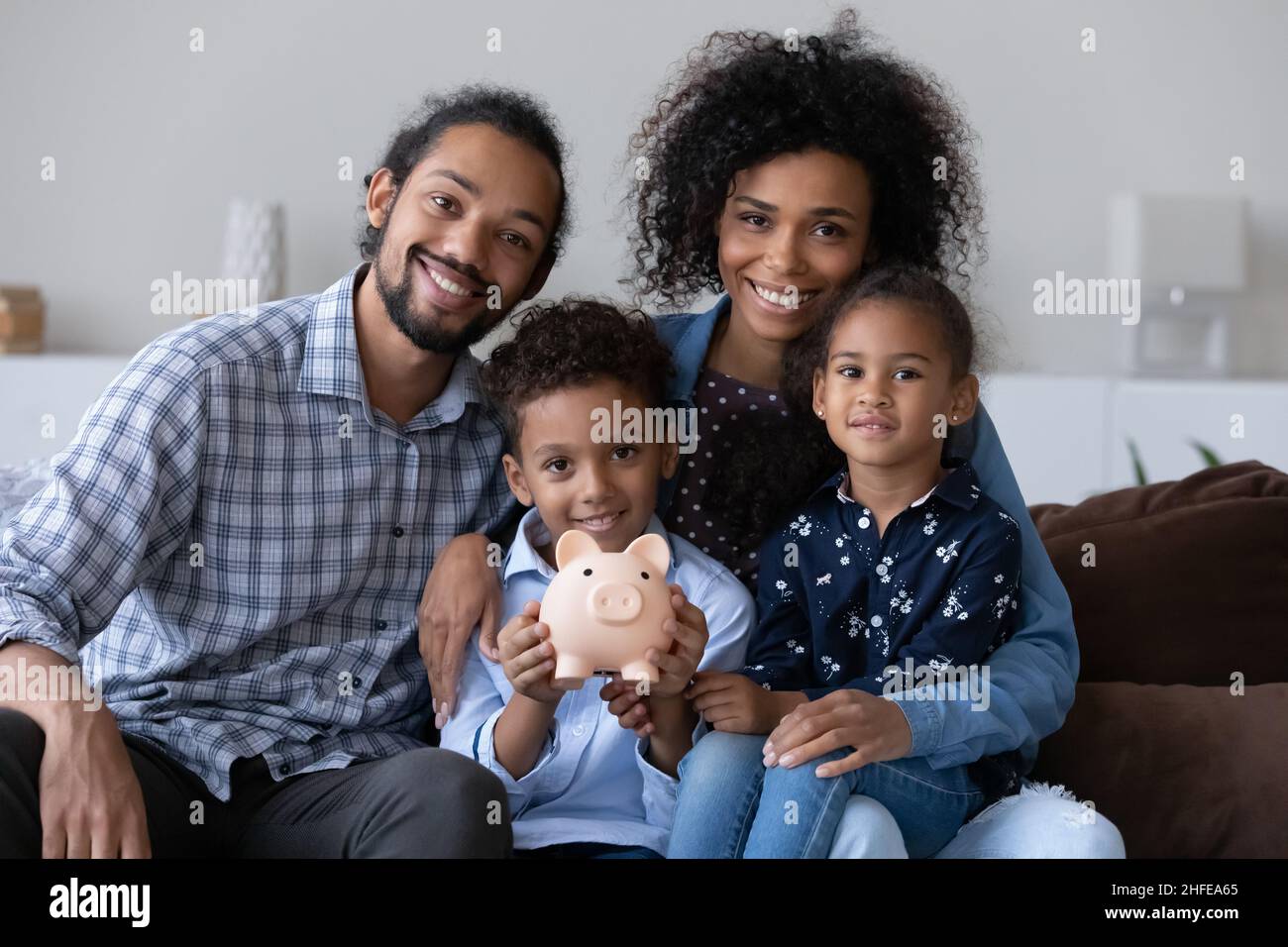 Happy Black family couple and little kids making financial reserve Stock Photo