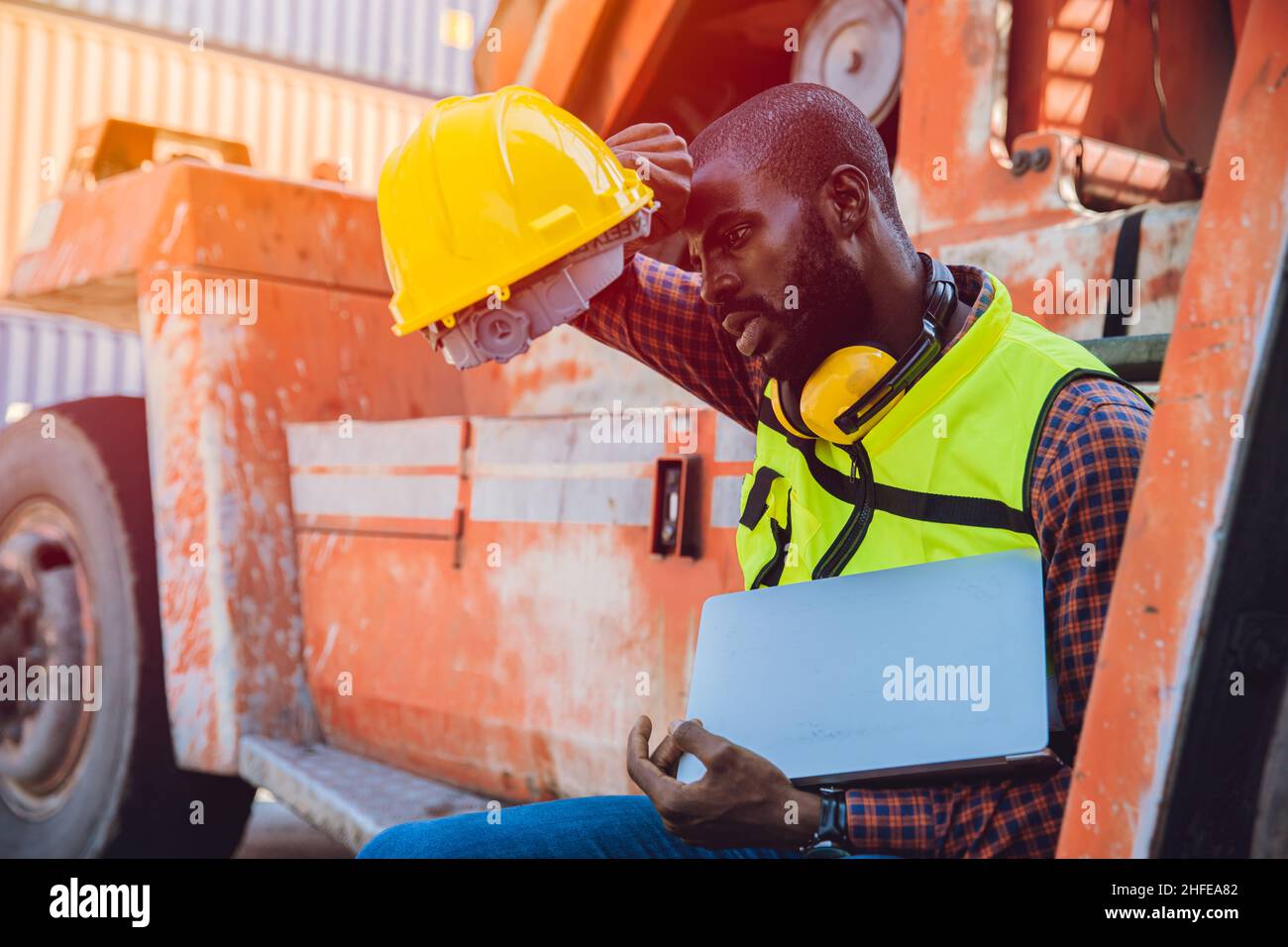 Tired stress worker sweat from hot weather in summer working in port goods cargo shipping logistic ground, Black African race people. Stock Photo