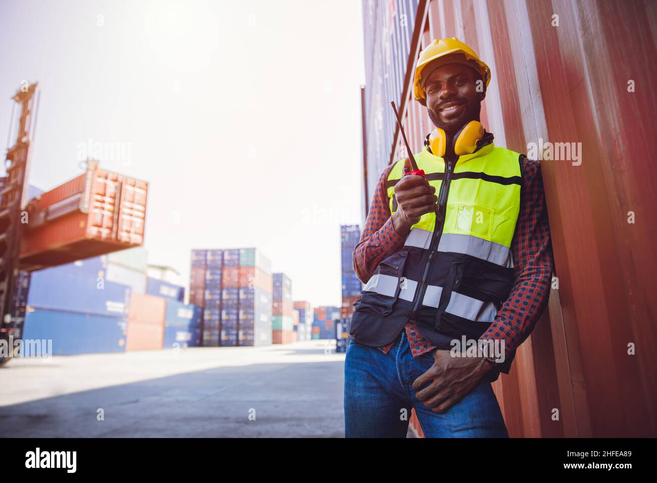 Portrait staff worker happy smile working in cargo shipping logistic port hand holding radio control. Stock Photo