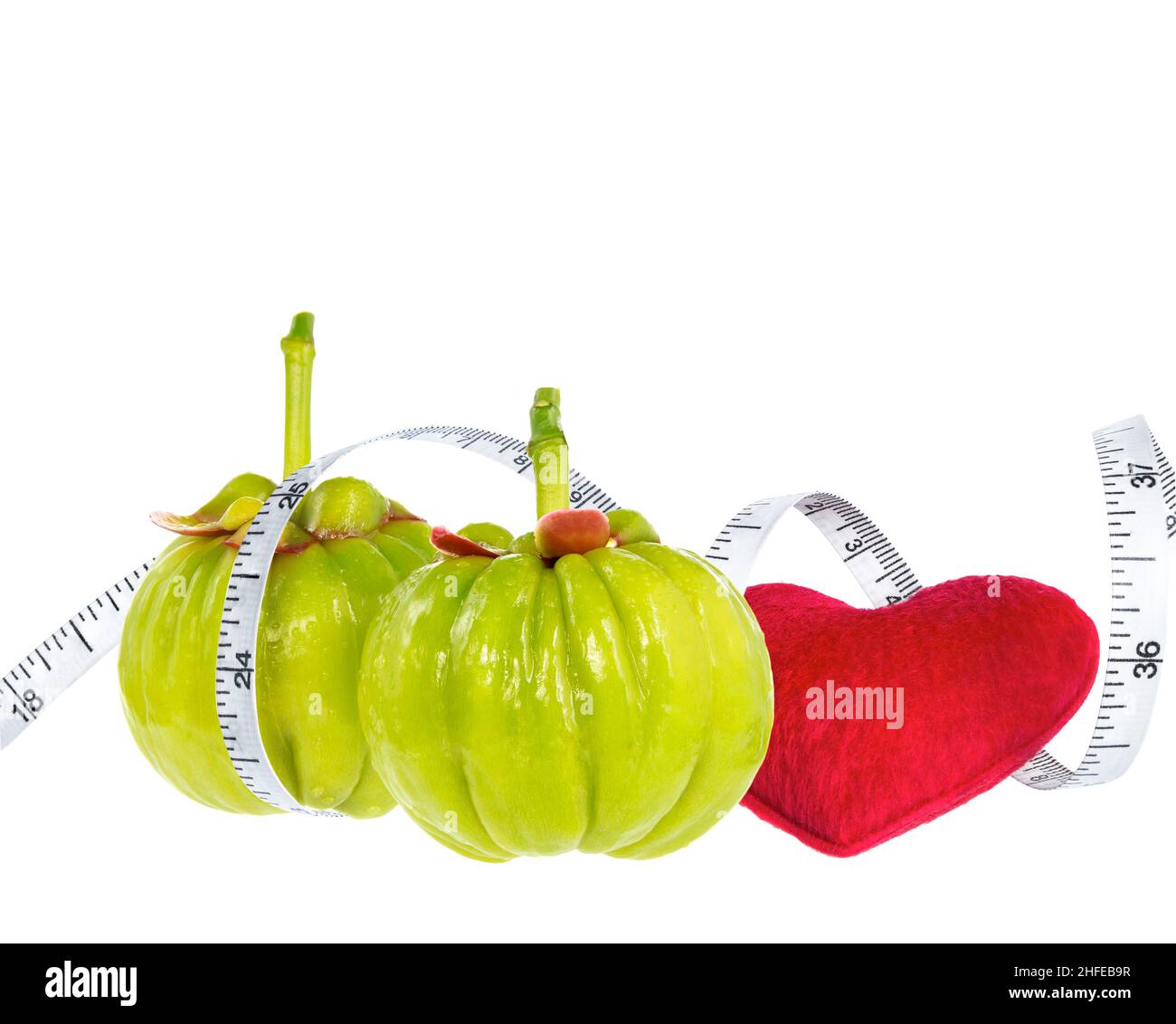 Garcinia cambogia fresh fruit with red heart and measuring tape, isolated on white. Garcinia is spice plants. It helps in the metabolism contain high Stock Photo