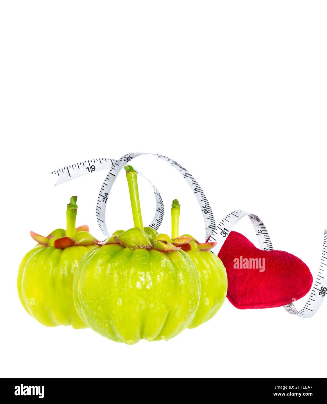 Garcinia cambogia fresh fruit with red heart and measuring tape, isolated on white. Garcinia is spice plants, contain high vitamin C and hydroxy citri Stock Photo