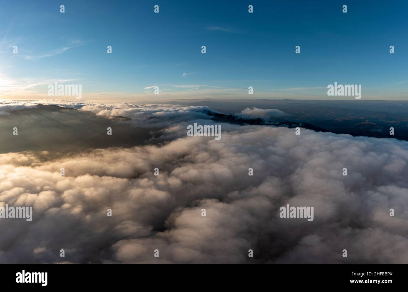Bright blue sky and thick layer of white fluffy clouds floating above ...