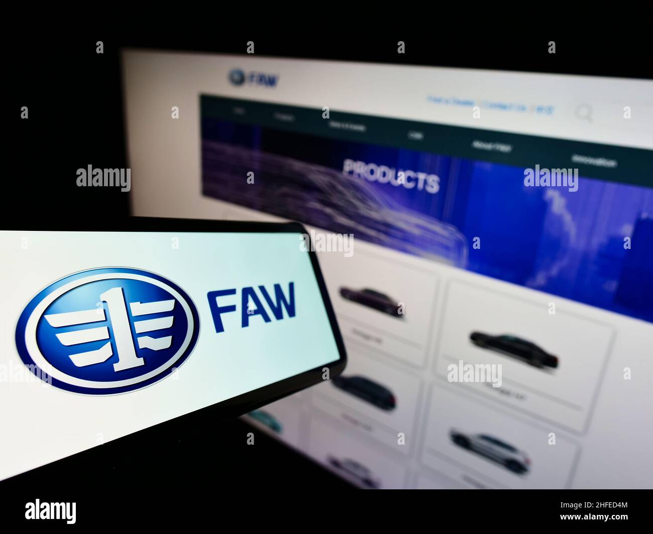 Cellphone with logo of Chinese automotive company FAW Group Corporation on screen in front of business website. Focus on left of phone display. Stock Photo