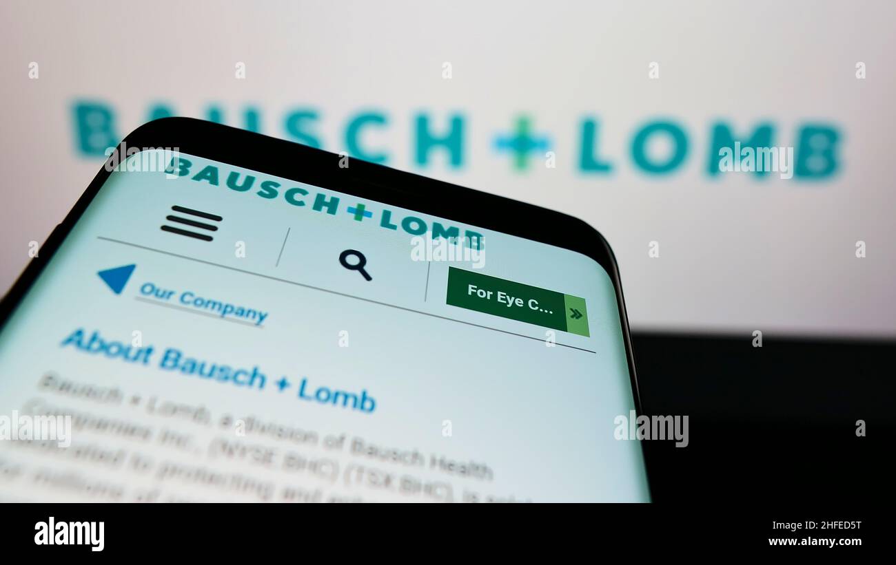 Mobile phone with webpage of Canadian eye health company Bausch + Lomb on screen in front of business logo. Focus on top-left of phone display. Stock Photo