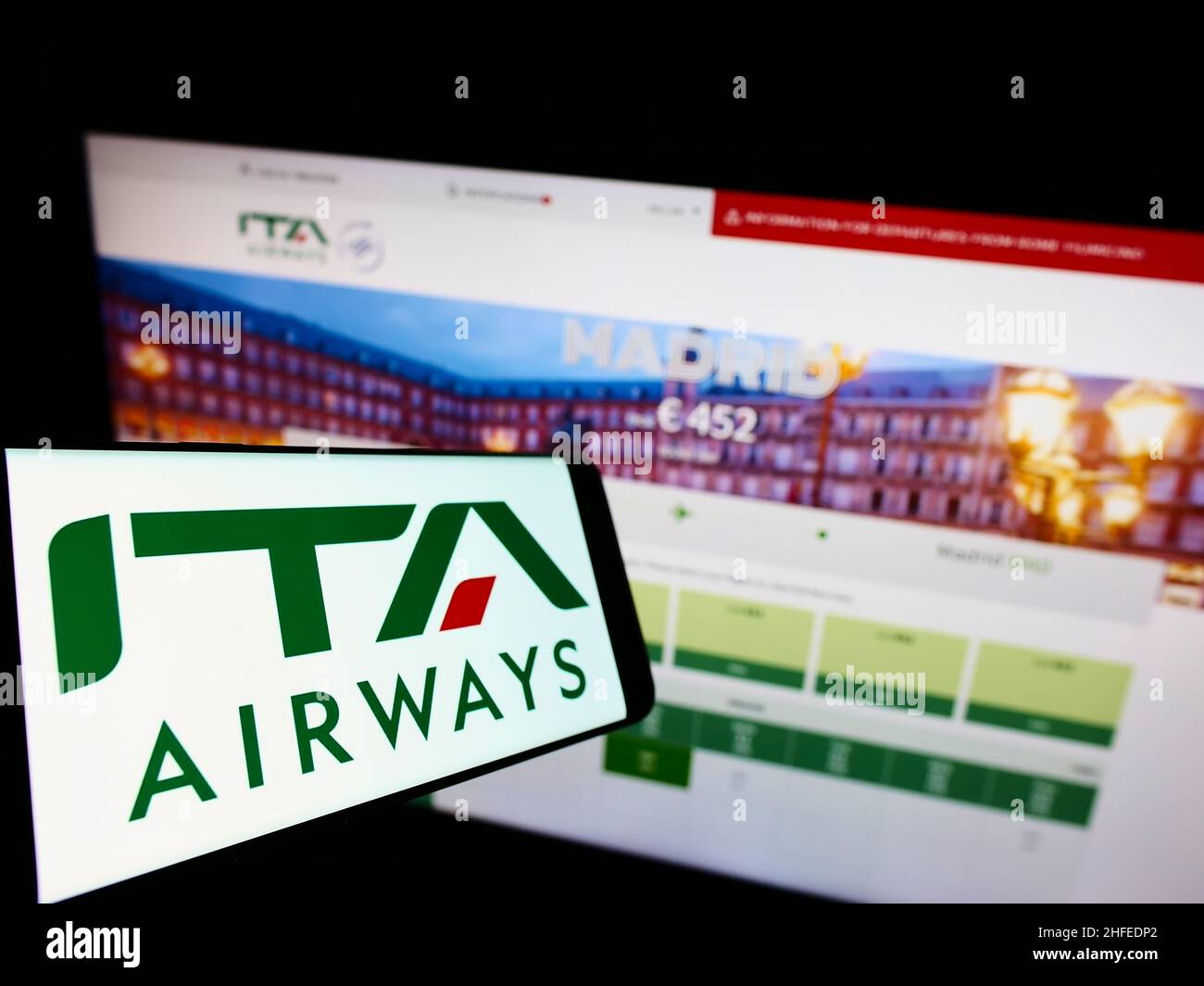 Smartphone with logo of airline company Italia Trasporto Aereo SpA (ITA Airways) on screen in front of website. Focus on center of phone display. Stock Photo