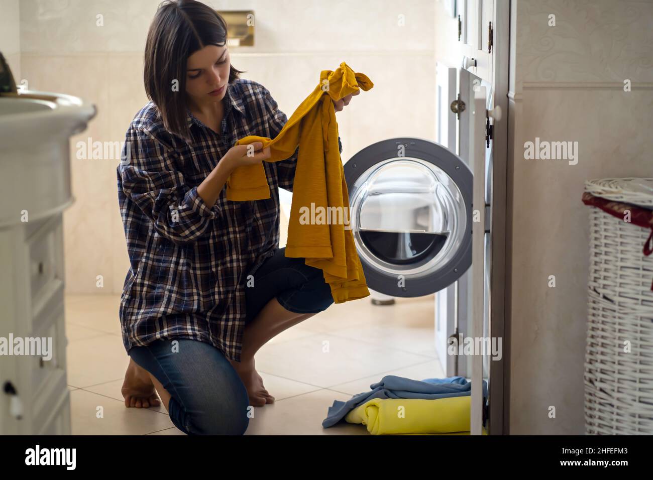 Young girl puts clothes in the washing machine Stock Photo - Alamy