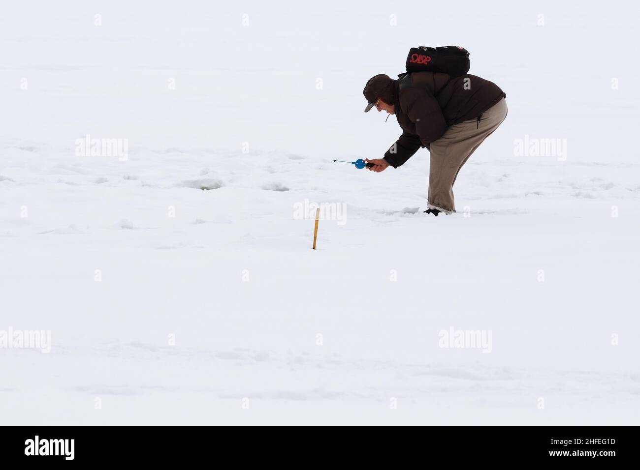 Winter fishing from the ice on the lake (reservoir) on a cold day. warmly dressed senior fishermen Stock Photo