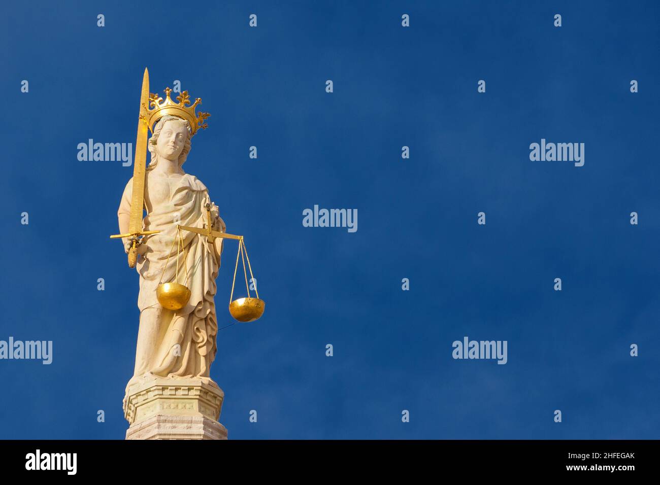 Lady Justice holding balance scales and sword, a 15th century medieval statue at the top of St Mark Basilica in Venice (with blue sky and copy space) Stock Photo