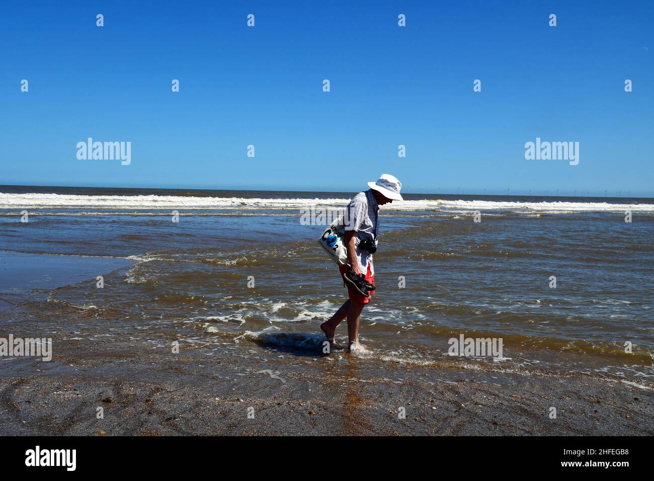 Man paddling in the sea at Chapel Six Marshes, Lincolnshire, UK Stock Photo