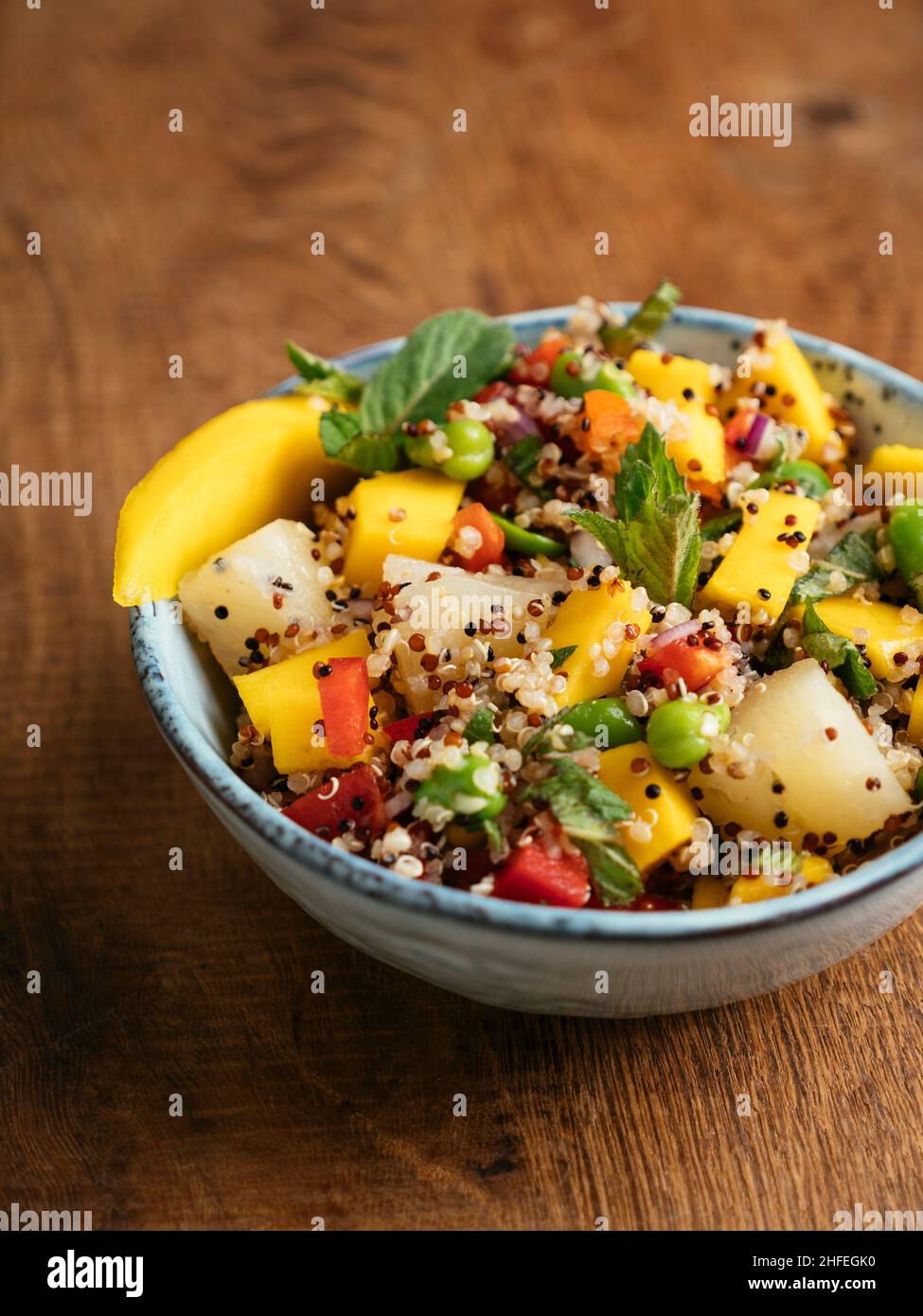 Tropical quinoa salad with mango, pineapple and fava beans. Stock Photo