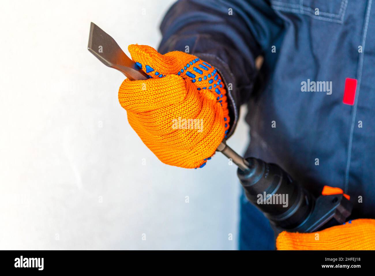 close-up. hands in protective gloves, hammer drill, installation of a chisel in a perforator. The concept of replacing the rotary drill. Stock Photo