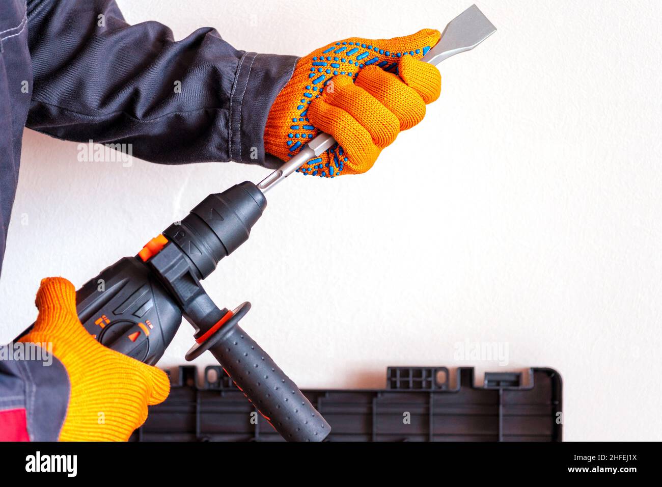close-up. hands in protective gloves, hammer drill, installation of a chisel in a perforator. The concept of replacing the rotary drill. Stock Photo