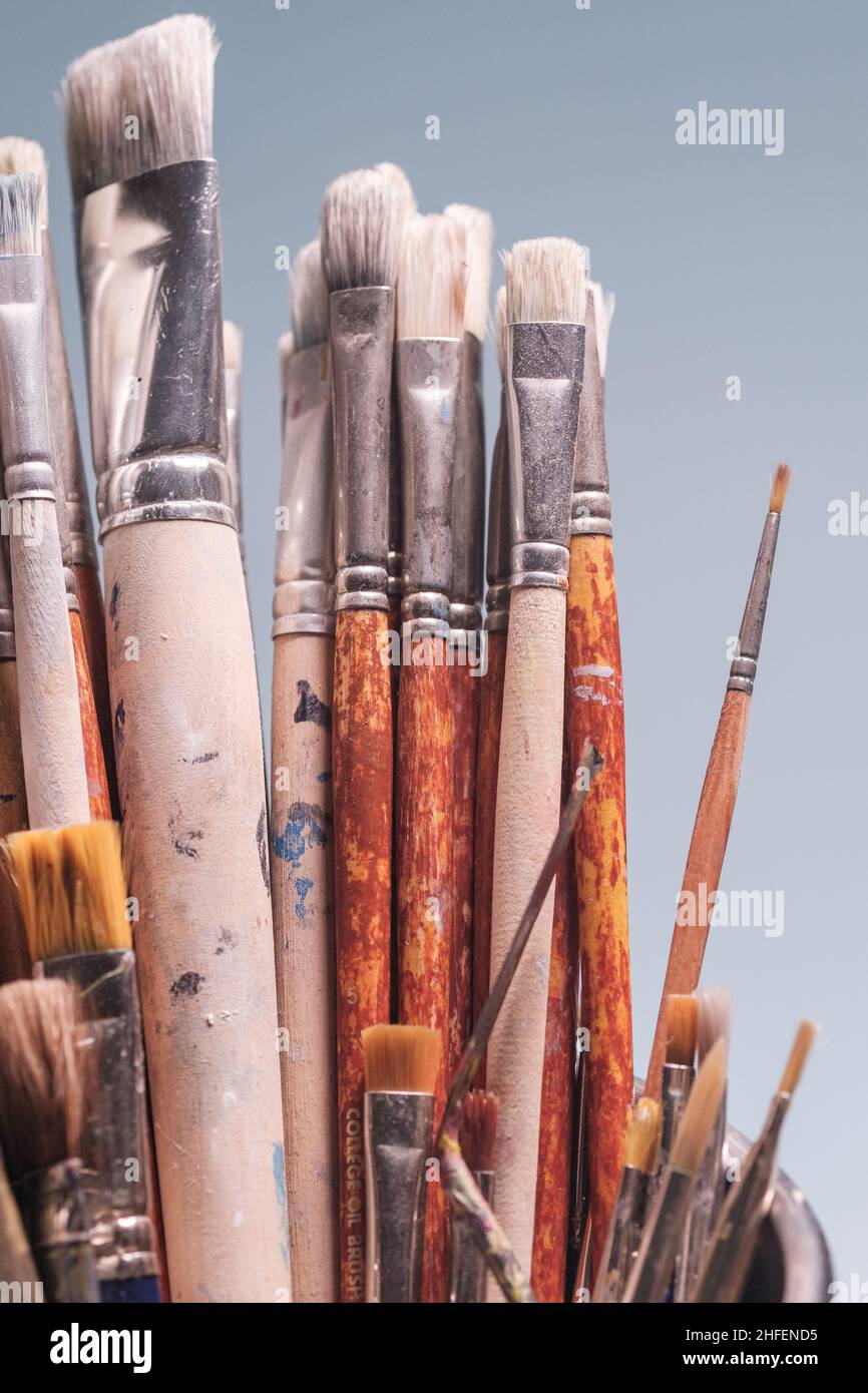 A bunch of grungy painter's brushes on plain blue background. Tools of creativity Stock Photo