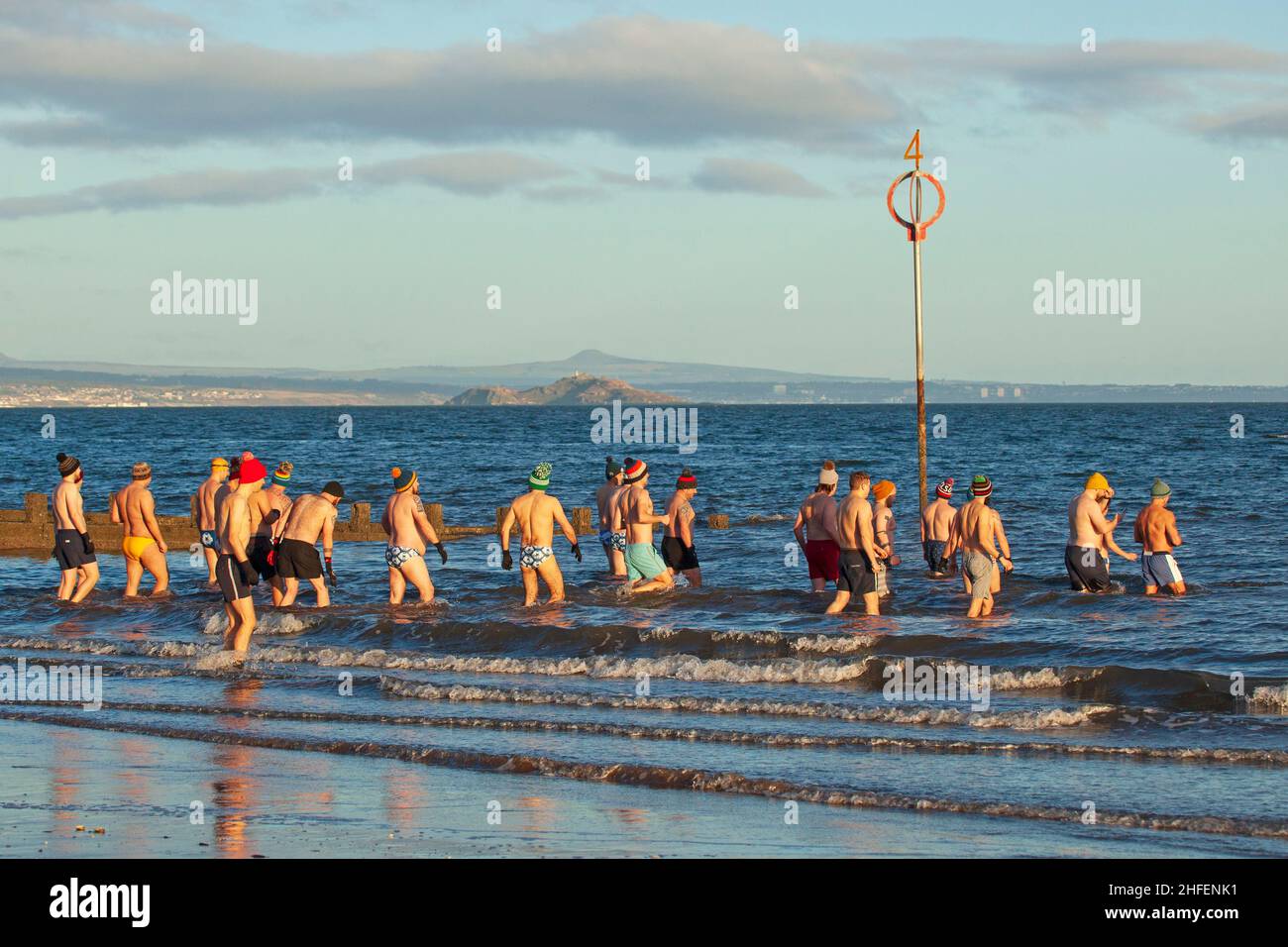 Portobello, Edinburgh, Scotland, UK. 16th January 2022. Finally sunrise sunshine with temperature of 7 degrees after a week of heavy cloud in the skies above the city. Pictured: Edinburgh Blueballs group get together at the seaside for a chilly dip in the Firth of Forth. Credit: Scottishcreative/Alamy Live News. Stock Photo