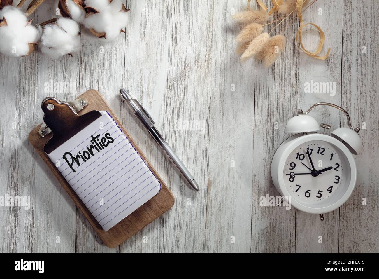 PRIORITIES text on notepad rustic wood flat lay with alarm clock and natural elements.  Time management concept. Stock Photo
