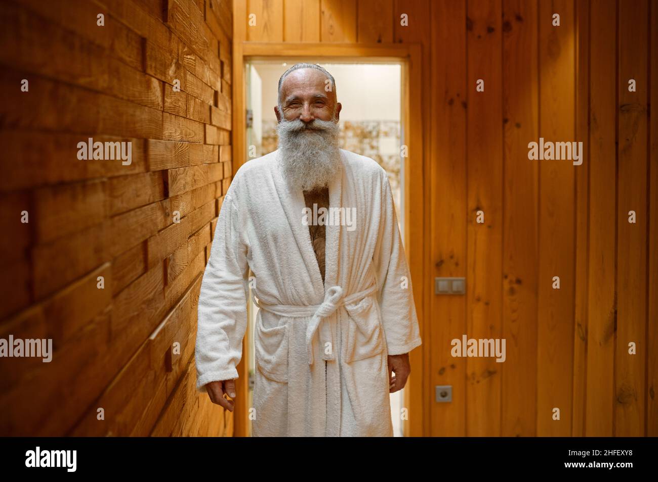 Smiling bearded man in bathrobe in sauna Stock Photo