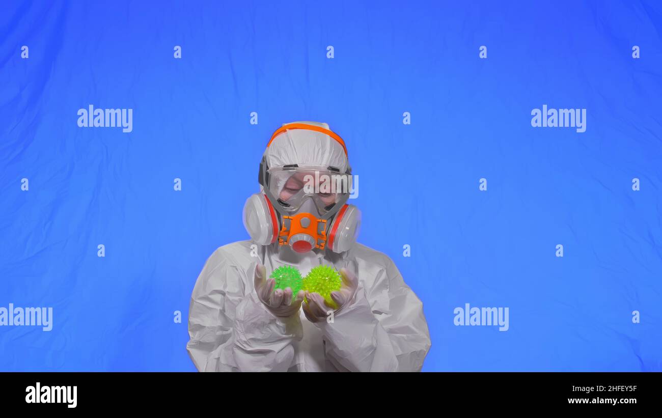 Doctor in respirator show a virus model concept health safety protection coronavirus epidemic 2019 nCoV. Slow motion. Woman wearing protect medical aerosol spray paint mask. Green ball spike thorn. Stock Photo