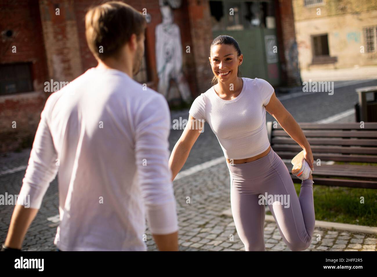 Sporty young woman doing stretching exercise after jogging with her personal trainer Stock Photo